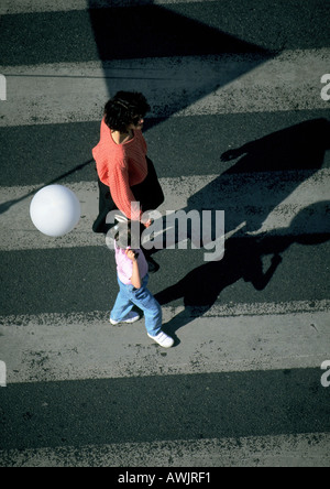 La donna e la giovane ragazza con palloncino, camminando su crosswalk, ad alto angolo di visione Foto Stock