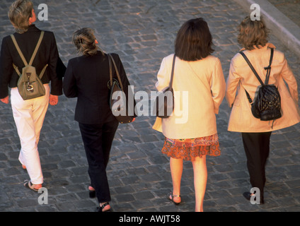 Quattro signore camminando sul ciottolato, angolo alto, vista posteriore. Foto Stock