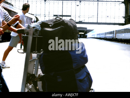 Persona spingendo i bagagli sul carrello alla stazione ferroviaria. Foto Stock