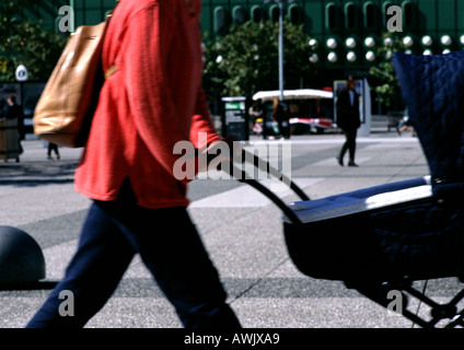 La donna a spingere un passeggino, nel quartiere finanziario, metà sezione Foto Stock
