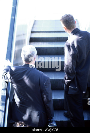 Imprenditori escalator di equitazione, in vista posteriore Foto Stock