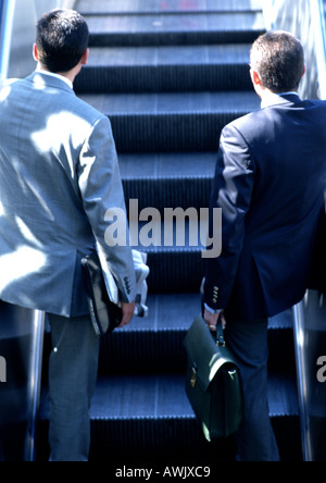 Imprenditori escalator di equitazione, in vista posteriore Foto Stock