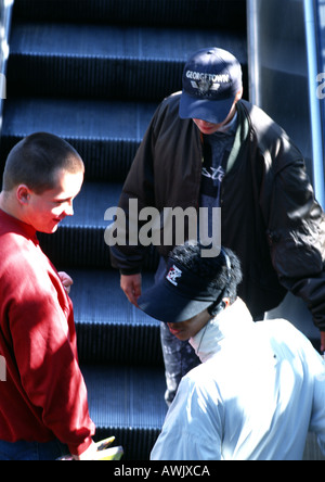 I giovani uomini a cavallo escalator, vista posteriore. Foto Stock