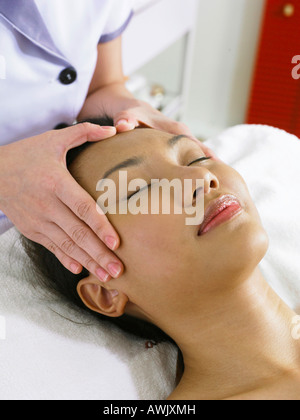 Giovane donna in corso di massaggio sulla sua fronte Foto Stock