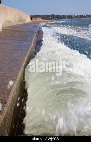 Un'onda rotoli sul mare difese a Avon Spiaggia Christchurch durante la marea massima dell'anno Foto Stock