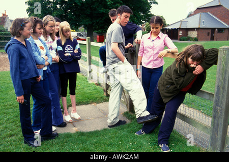 Gruppo di adolescenti bullismo sovrappeso giovane ragazza nel parco giochi Foto Stock