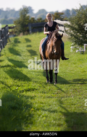 Donna bionda con il proprio cavallo marrone Foto Stock