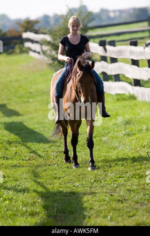 Donna bionda con il proprio cavallo marrone Foto Stock