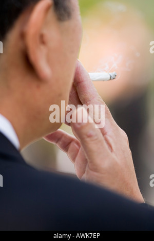 L'uomo tiene una sigaretta in mano Foto Stock