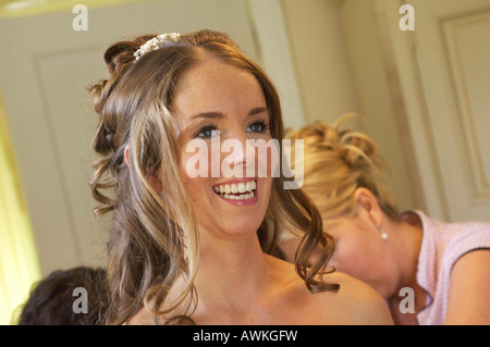 Sposa sempre pronto e mettendo il tocco finale assistita da sua damigella Foto Stock