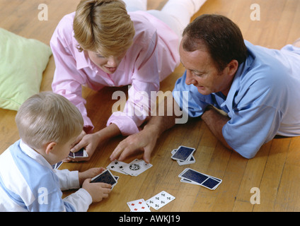 I genitori a giocare a carte con il bambino, sul pavimento, ad alto angolo di visione Foto Stock