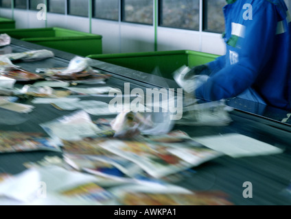 Lavoratore carta di smistamento sul nastro trasportatore per il riciclaggio Foto Stock