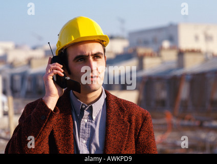 Uomo che indossa elmetto, tramite telefono cellulare Foto Stock
