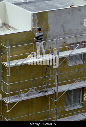 Lavoratore sui ponteggi, parete di verniciatura Foto Stock