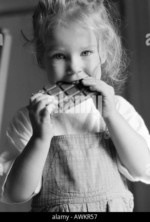 Ragazza mangiando cioccolato bar, b&W Foto Stock