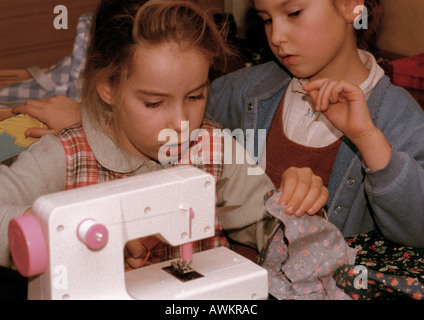 Due ragazze affiancate, utilizzando una macchina da cucire Foto Stock