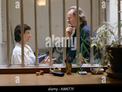 Donna e uomo faccia a faccia, visto attraverso le rotaie sulla finestra Foto Stock