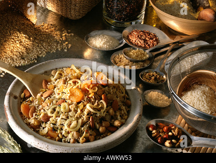 Piatto cucinato di riso con frutta secca e noci, circondato da vari grani secco e semi Foto Stock