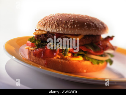 Cheeseburger con pomodori, lattuga, e pancetta sui semi di sesamo bun, close-up Foto Stock