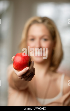Sorridente giovane donna bionda tenendo una mela rossa, focus su apple Foto Stock