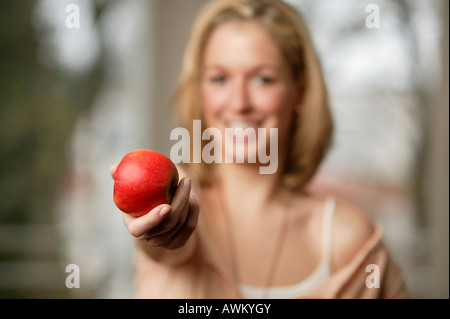 Sorridente giovane donna bionda tenendo una mela rossa, focus su apple Foto Stock