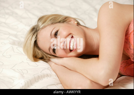 Sorridente bionda e giovane donna giaceva a letto Foto Stock