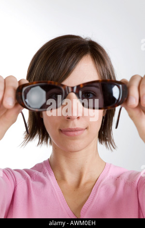 Giovane donna guardando attraverso occhiali da sole Foto Stock