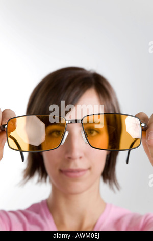 Giovane donna guardando attraverso occhiali da sole Foto Stock