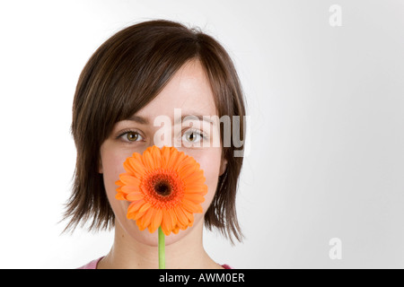 Giovane donna con un fiore nella parte anteriore del viso Foto Stock