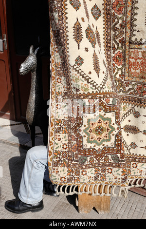 Venditore seduti all'ombra dietro un bellissimo tappeto berbero, Marrakech, Marocco, Africa Foto Stock