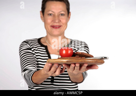 Donna che offre il vassoio con cibi integrali Foto Stock