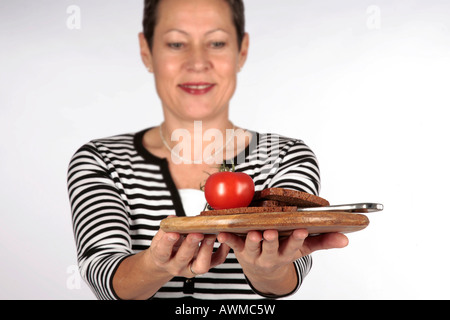 Donna sorridente che offre il vassoio con cibi integrali Foto Stock