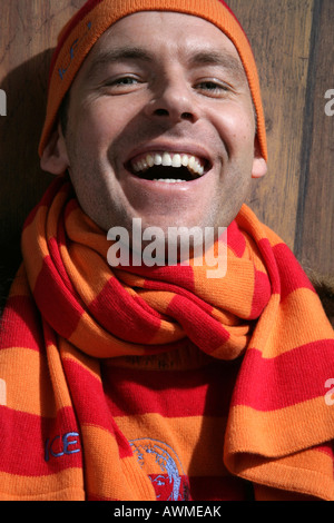 Giovane uomo che indossa un cappello di lana e sciarpa, ridendo Foto Stock