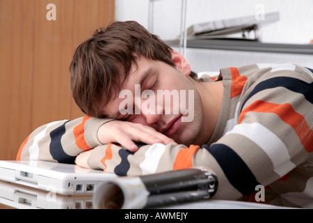 Giovane uomo di dormire sulla scrivania Foto Stock