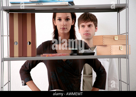 Il giovane e la giovane donna in piedi dietro uno scaffale Foto Stock