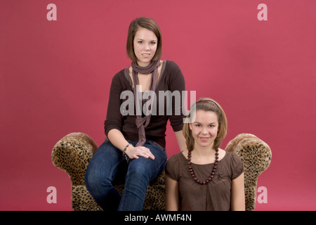 Due ragazze, pre-adolescenti, dai primi anni dell'adolescenza seduto su una tigre del lettino di stampa Foto Stock