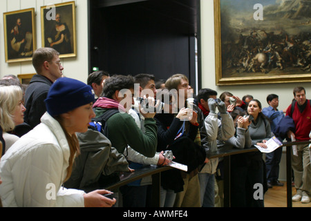 I turisti in cerca di dipingere la Mona Lisa di Leonardo da Vinci sul display dietro la sua bullet proof schermo nell'arte del Louvre Foto Stock