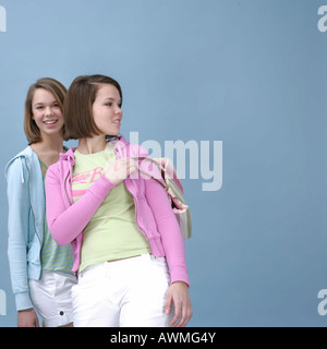 Due ragazze che indossano abiti casual passeggiando davanti a una luce di sfondo blu Foto Stock