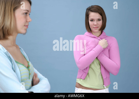 Due ragazze che indossano abiti informali davanti a una luce di sfondo blu Foto Stock