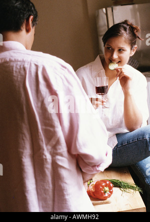 Donna di mangiare e tenendo il vetro, vista posteriore dell'uomo in primo piano sfocato Foto Stock