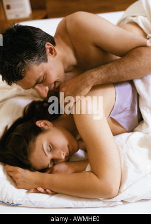 Coppia giacendo in letto, l'uomo tocca alle spalle della donna Foto Stock