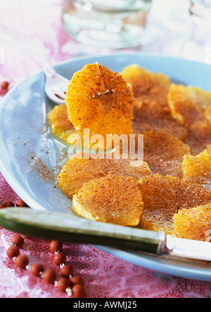 Fettine di arancia cosparsi di cannella sulla piastra, close-up Foto Stock