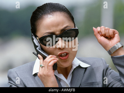 Imprenditrice parlando al cellulare, gesticolando in modo aggressivo Foto Stock