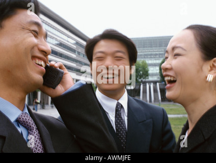 Tre gli imprenditori a ridere, uno tramite telefono cellulare Foto Stock