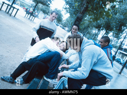 Un gruppo di giovani riuniti intorno a una panchina nel parco Foto Stock