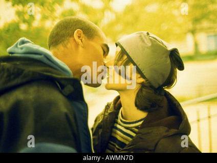 Coppia giovane kissing, vista laterale Foto Stock