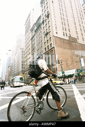 Uomo in Bicicletta Equitazione in street, edifici in background Foto Stock