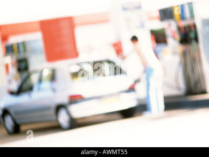 Persona riempimento auto presso la stazione di gas, offuscata Foto Stock