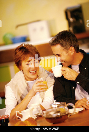 L uomo e la donna seduta al tavolo avente la colazione, sorridente Foto Stock