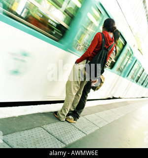 I giovani in piedi sulla piattaforma accanto al movimento di treno della metropolitana Foto Stock